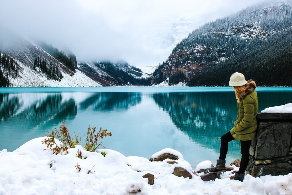 A woman hiker standing near the lake surrounded by snow