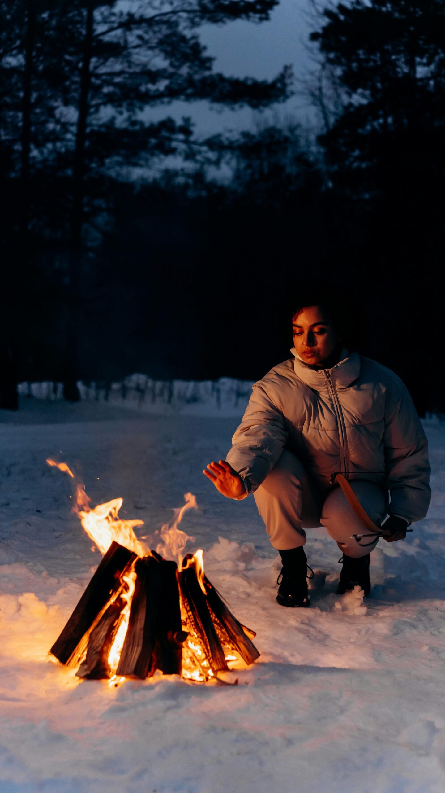 Woman warms up by a fire in the snow