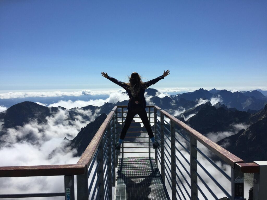 A woman jumping to celebrate reaching peak of her adventure.
