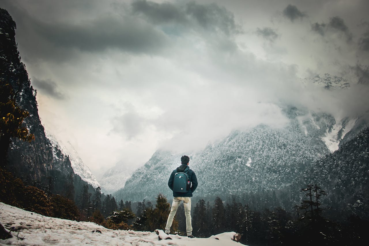 Unrecognizable traveler standing on snowy mountain peak