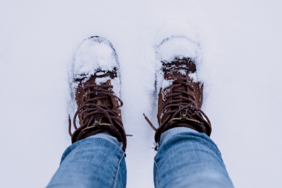A person with brown winter boots walking snow.